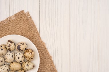 Ahşap arka plan üzerinde beyaz bir tabak içinde taze bıldırcın yumurtası