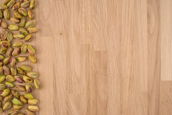 Roasted pistache nuts on natural wooden table background, healt — Fotografia de Stock