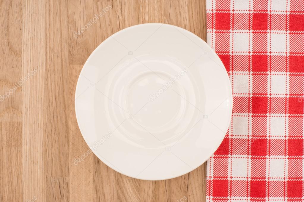 Empty plate on wooden tabletop with tablecloth