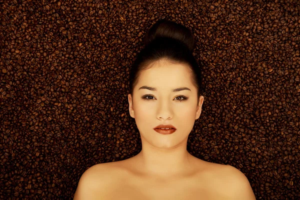 Attractive woman lying in coffee grains. — Stock Photo, Image