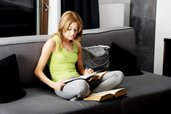 Młoda kobieta, czytając książkę na kanapie. — Zdjęcie stockowe