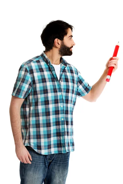 Young man pointing with big red pencil. — Stock Photo, Image