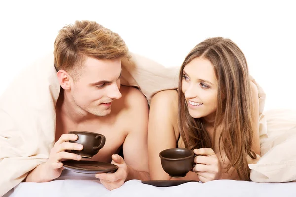 Glückliches Paar trinkt Kaffee im Bett. — Stockfoto