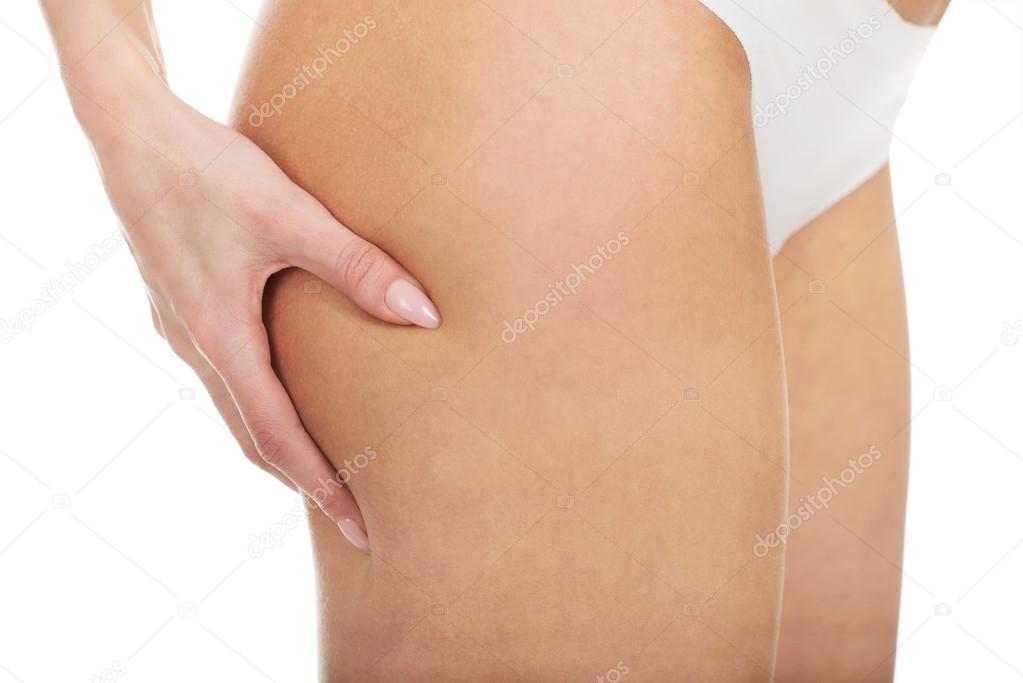 Slim woman pinching her thigh.