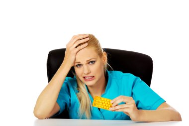 Şok ve korkmuş kadın hemşire ya da doktor arkasında oturan Resepsiyon ve paket hap holding