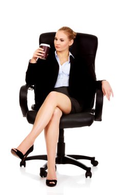Tired business woman sitting on wheel chair with cup of coffee clipart