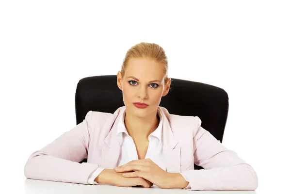 Jeune femme d'affaires sérieuse assise derrière le bureau — Photo