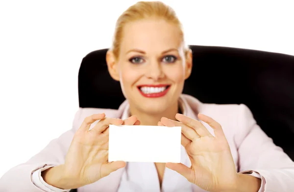 微笑的女商人坐在桌子后面，持空商务卡 — 图库照片