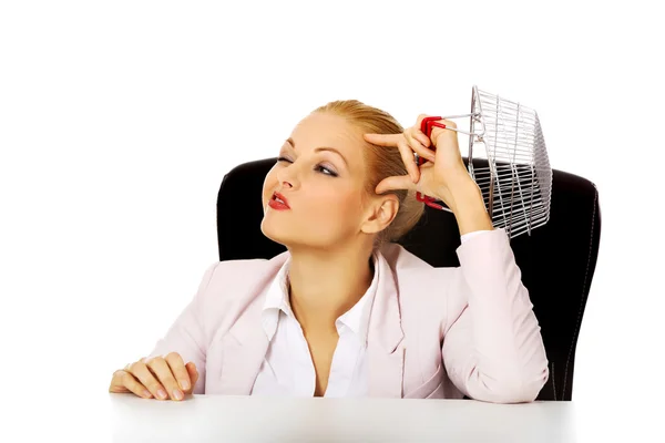 Smile business woman sitting behind the desk and holding small shopping basket — Stock Photo, Image