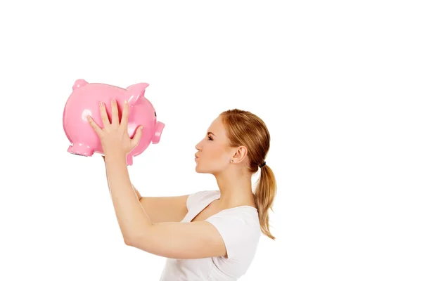 Happy young woman kissing a piggybank — Stock Photo, Image