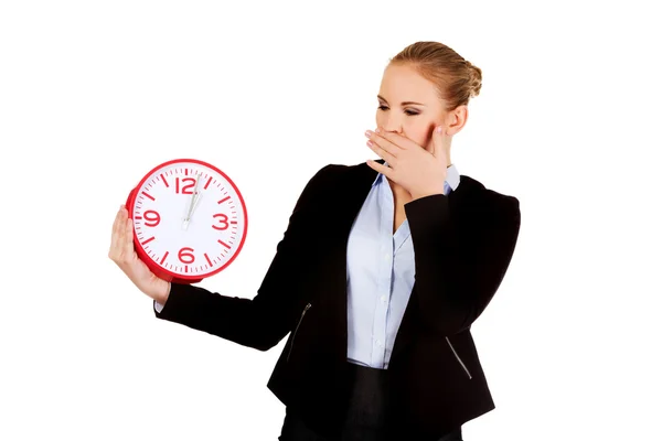 Yawning business woman holding office clock — Stock Photo, Image