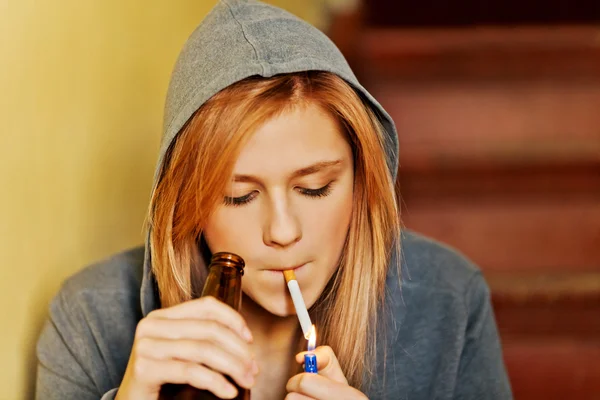 Teenage woman drinking beer and smoking cigarette