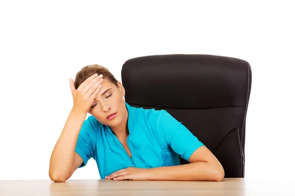 Tired young female doctoror nurse sitting behind the desk — Stock Photo, Image