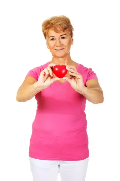 Gamla leende kvinna med röd toy hjärta — Stockfoto