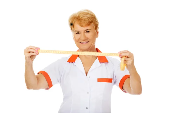 Sourire médecin âgé ou infirmière tient ruban à mesurer — Photo