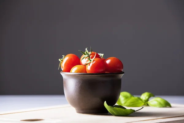 Спелые помидоры в миске и базилике — стоковое фото