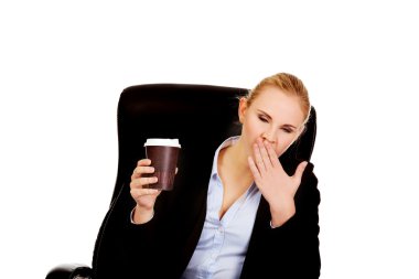 Yawning business woman sitting on wheel chair and holding cup of coffee clipart