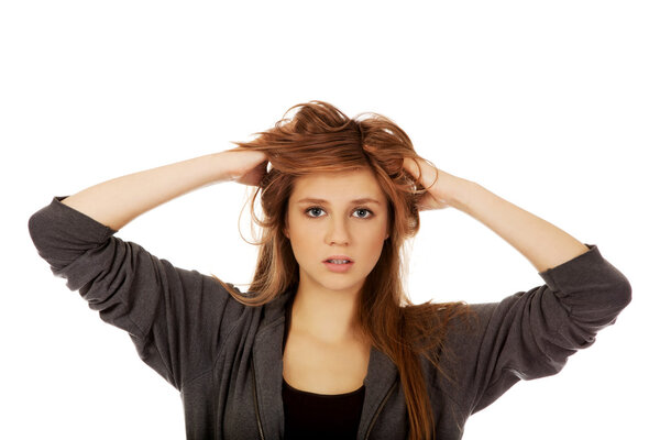 Молодая удивленная женщина держит руки внутри волос
