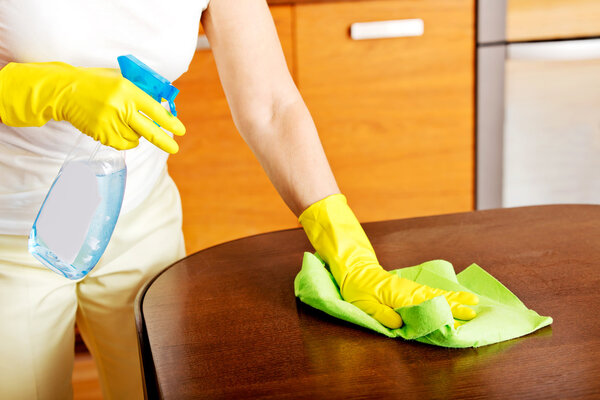 Elderly woman in yellow gloves cleaning table