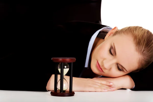Jovem mulher de negócios dormindo na mesa com ampulheta — Fotografia de Stock
