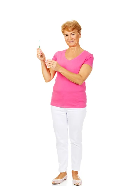 Smiling senior woman holding toothpaste and toothbrush — Stock Photo, Image