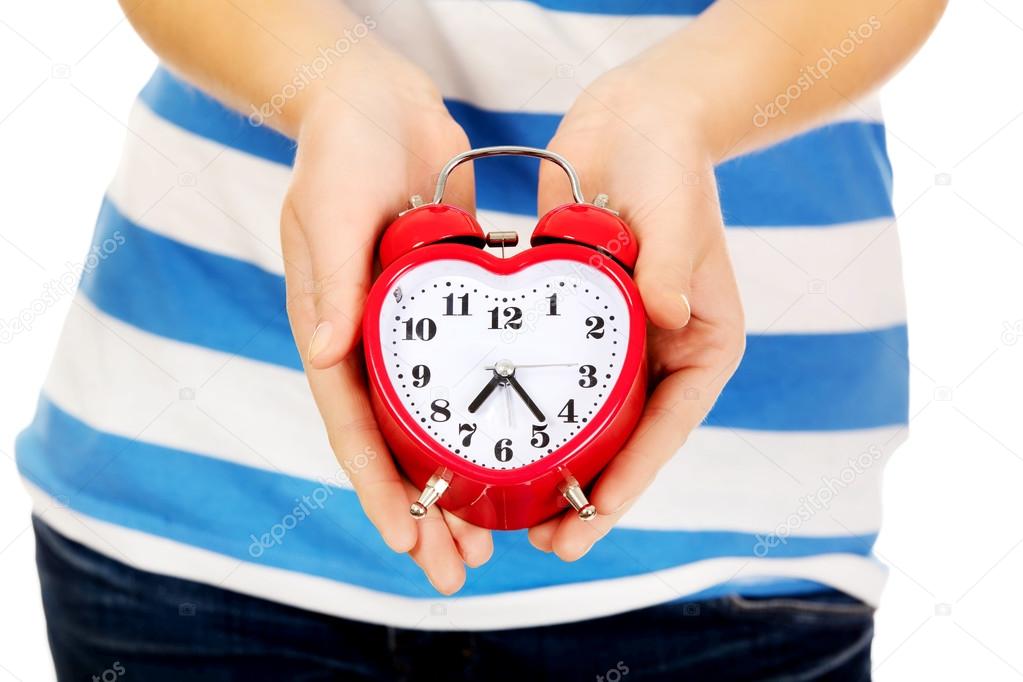Teenage woman showing alarm clock