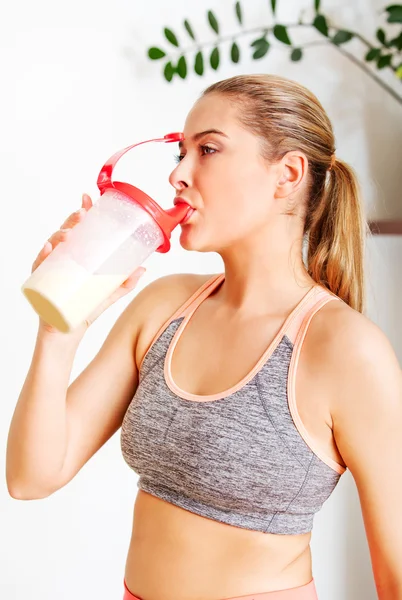 Молодая спортсменка пьет протеиновый коктейль — стоковое фото