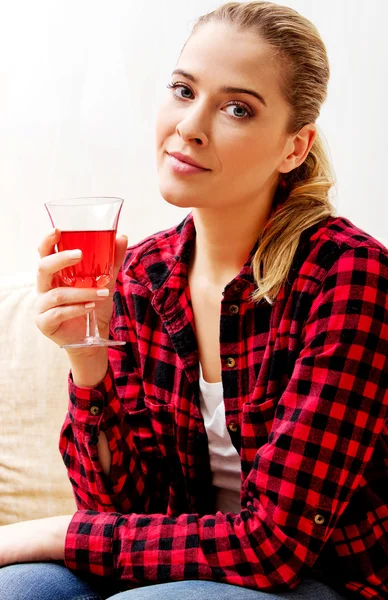 Jeune femme assise sur le canapé et buvant du vin — Photo