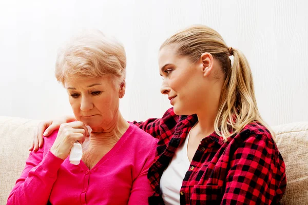 Mother and daughter sitting on couch, daughter comforting her  mother — Stock Photo, Image