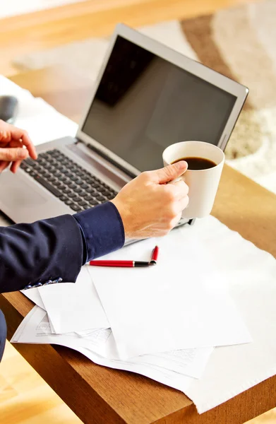 Man arbetar på laptop och dricka kaffe hemma — Stockfoto