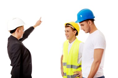 Kadın mühendis iki inşaatçıyla konuşuyor.