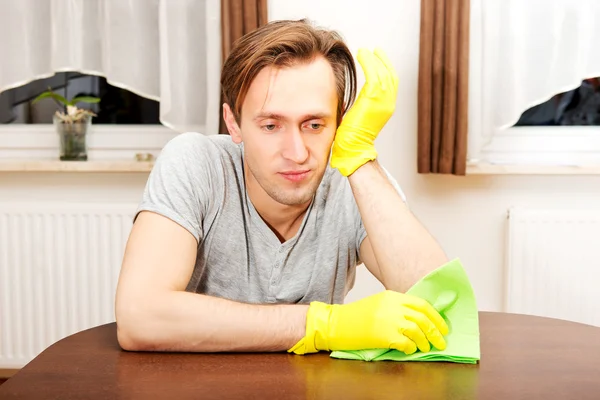 Müder Mann in gelben Handschuhen sitzt hinter dem Schreibtisch — Stockfoto