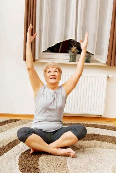 Senior vrouw doet yoga in de woonkamer — Stockfoto