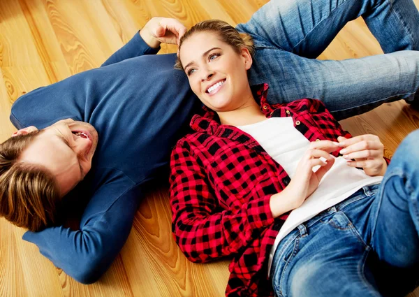 Jovem casal feliz deitado no chão — Fotografia de Stock