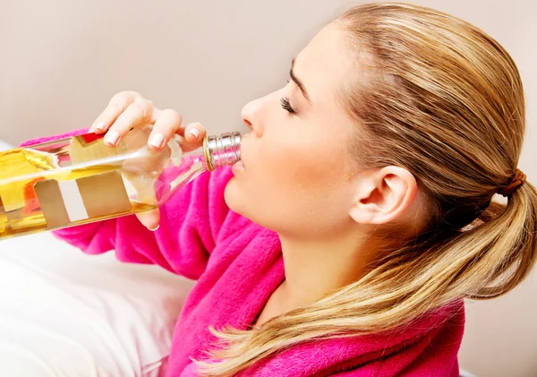 Jonge bezorgde vrouw drinkt alcohol in bed — Stockfoto