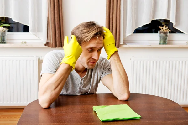 Tired man in yellow gloves sitting behind the desk — Stock Photo, Image