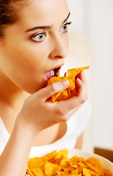 Junge Frau schaut fern und isst Chips — Stockfoto