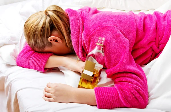 Jovem preocupada mulher bebendo álcool na cama — Fotografia de Stock