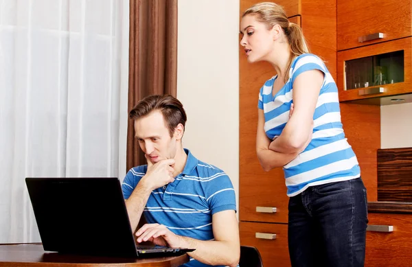 Man watching something on laptop, his wife trying to look what he doing — Stock Photo, Image