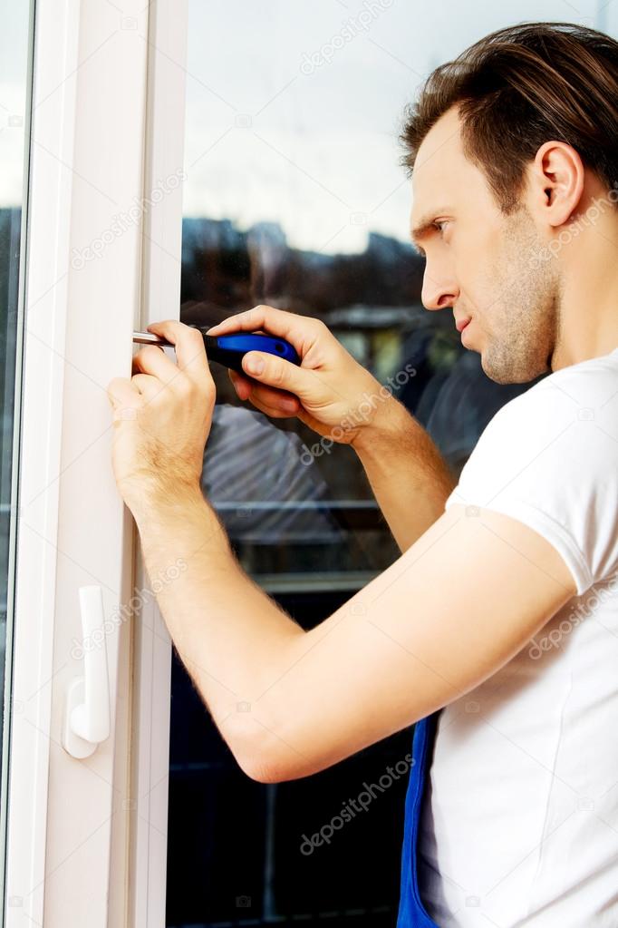 Young handyman repair window with screwdriver