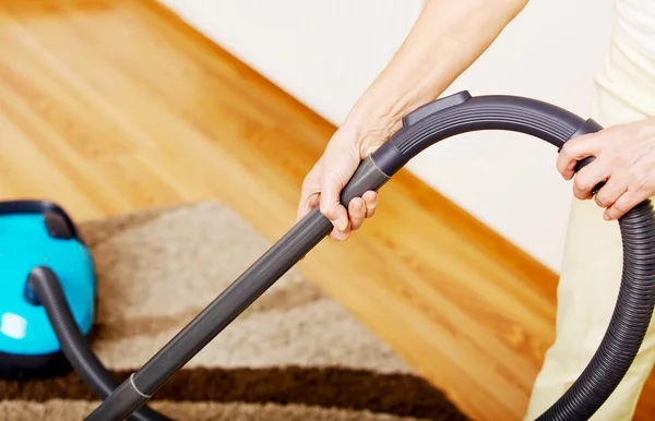 Wanita senior membersihkan karpet di rumah. — Stok Foto