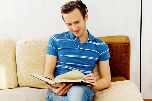 Mann sitzt auf Couch und liest Buch — Stockfoto