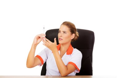 Masanın arkasında oturan ve şırınga tutarak kadın doktor