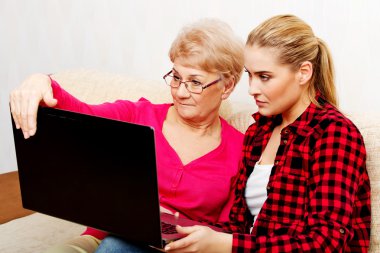 Anne ve kızı kanepede oturan ve laptop bir şey izliyor