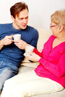 Anne ve oğlu kanepede oturan ve çay veya kahve içme