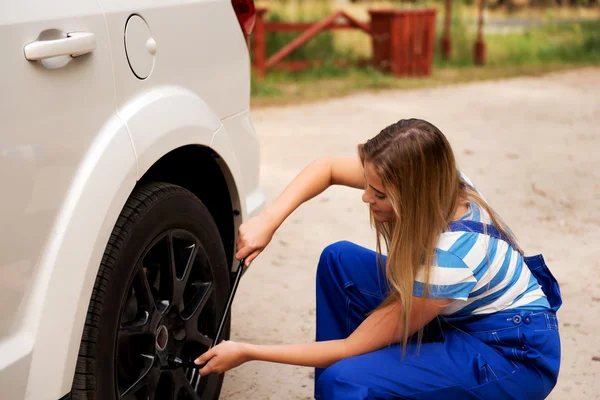 Female mechanic changing tire with wheel wrench — Stock Photo, Image