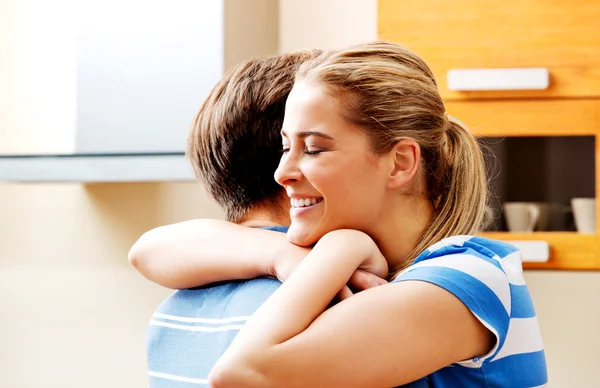 Feliz joven pareja abrazándose en la cocina — Foto de Stock