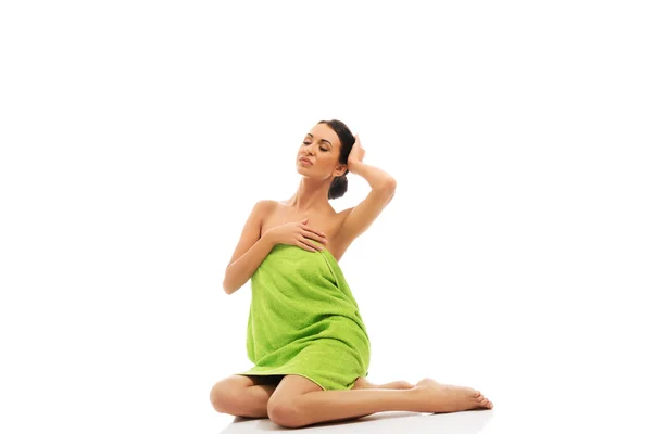 Krásná žena sedí zabalená do ručníku — Stock fotografie