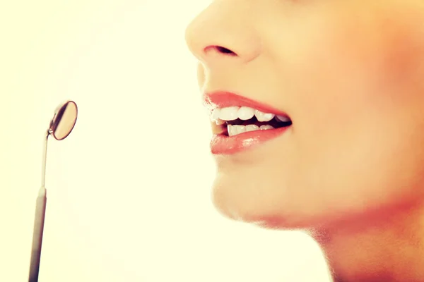 Ung kvinna tänder och en tandläkare mun spegel — Stockfoto