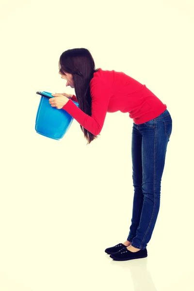 Jovem mulher vomitando para balde . — Fotografia de Stock